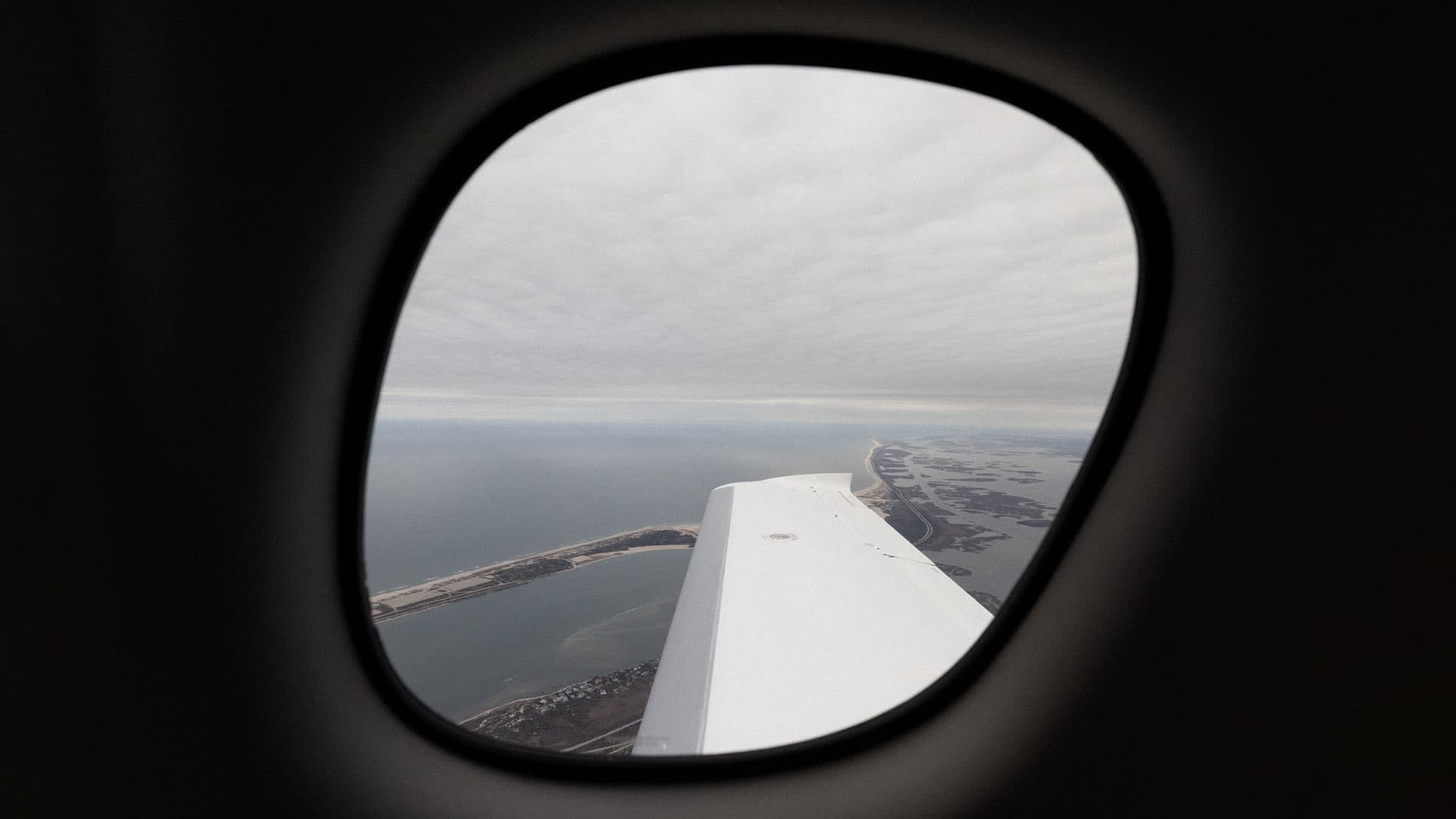 Aerial view of coastline and ocean through an airplane window.